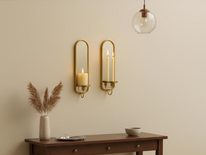 Brass wall candle holders with arched mirrors, displayed with a lit pillar candle and two lit taper candles