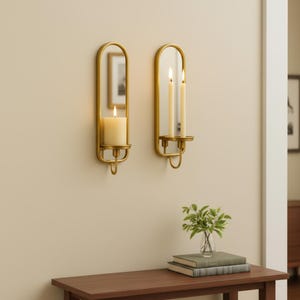 Brass wall candle holders with arched mirrors, displayed with a lit pillar candle and two lit taper candles