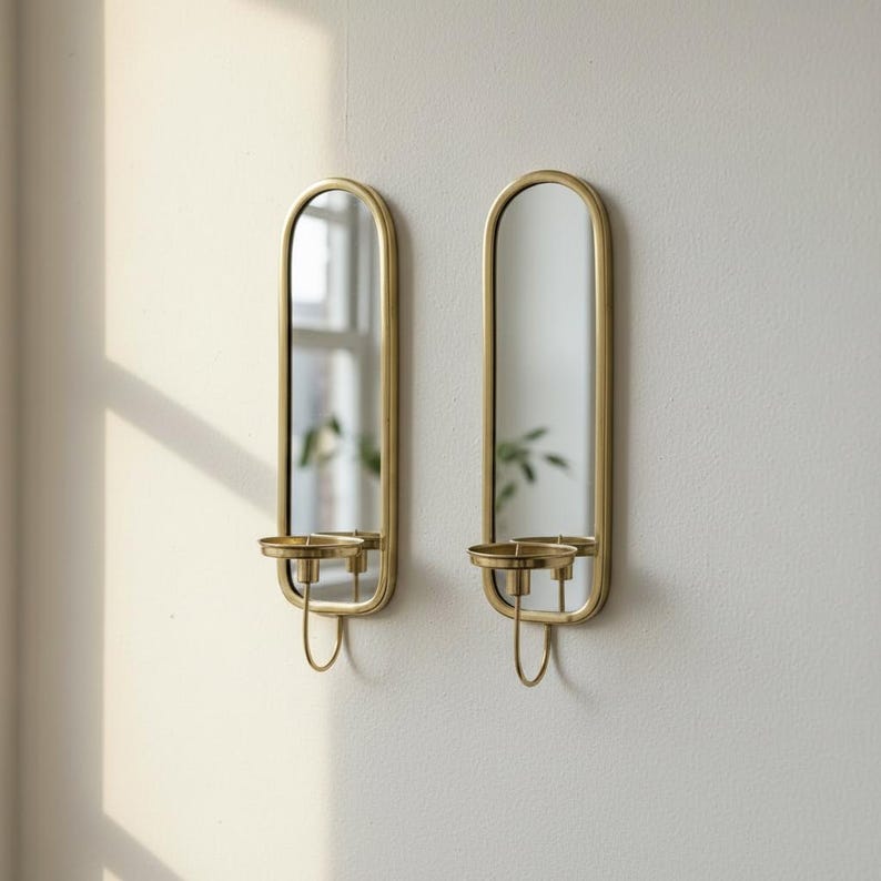 Brass wall candle holders with arched mirrors, displayed with a lit pillar candle and two lit taper candles