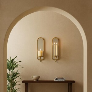 Brass wall candle holders with arched mirrors, displayed with a lit pillar candle and two lit taper candles