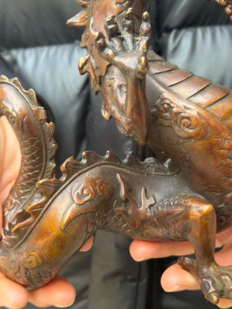 K&ouml;nnte beinhalten: Eine detaillierte Bronzedrachenskulptur mit komplizierten Schuppen und Krallenf&uuml;&szlig;en. Der K&ouml;rper des Drachen ist warmbraun mit dunkleren Akzenten, und es scheint sich um einen dekorativen Gegenstand zu handeln.