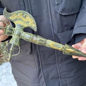May include: An antique bronze-colored ritual dagger with intricate dragon and geometric designs. The dagger features a curved blade, a detailed handle, and a decorative pommel. The overall length is approximately 12 inches.