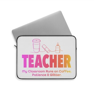 Puede incluir: Funda para portátil blanca con borde negro. La funda tiene un gráfico rosa, naranja y amarillo de una taza de café, una botella de pegamento y una goma de borrar con el texto "TEACHER" en un degradado de rosa, naranja y amarillo. Debajo del gráfico está el texto "My Classroom Runs on Coffee, Patience & Glitter."