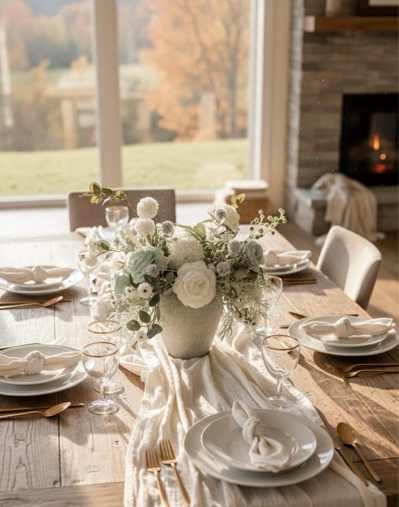 K&ouml;nnte beinhalten: Ein sch&ouml;n gedeckter Esstisch mit einem Blumengesteck. Der Tisch ist aus hellem Holz gefertigt und mit wei&szlig;en Tellern, goldger&auml;nderten Gl&auml;sern und goldenem Besteck gedeckt. Ein wei&szlig;er Tischl&auml;ufer und Servietten vervollst&auml;ndigen das elegante Ambiente.
