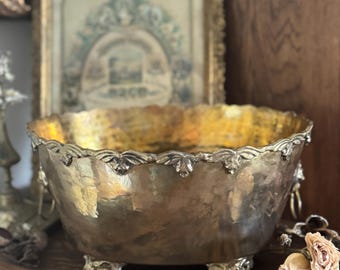 Macetero antiguo de latón con patas y detalles de cabezas de león.