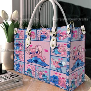 Op de afbeelding: Een rechthoekige handtas met een herhalend rasterpatroon van blauwe en roze panelen. Het ontwerp toont de tekenfilmfiguren Stitch en Angel in verschillende houdingen met hartjes. De tas heeft witte handvatten, goudkleurige hardware en de tekst HELLO.