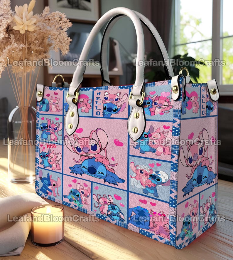 Op de afbeelding: Een rechthoekige tote bag met een herhalend patroon van blauwe en roze stripfiguren in verschillende houdingen met hartjes. De tas heeft witte handvatten bevestigd met goudkleurige hardware en bevat de tekst "HELLO" en "Kiss" erop gedrukt.