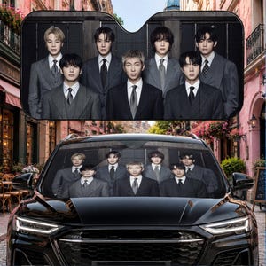 Puede incluir: Un parasol para parabrisas de coche en color negro que presenta una impresión fotográfica de alta resolución de siete personas vestidas con trajes formales de rayas gris carbón, camisas blancas y corbatas oscuras, dispuestas en un retrato grupal.