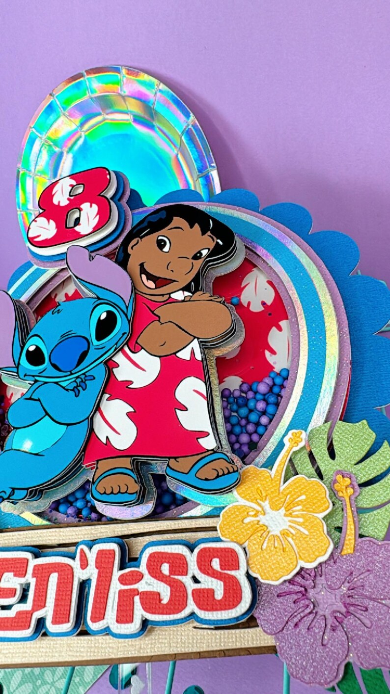 Może przedstawiać: Wielowarstwowa, kolorowa dekoracja na tort urodzinowy z postaciami Lilo i Stitch. Projekt zawiera cyfrę 8, czerwono-białe wzorzyste tło i słowo "enilss". Elementy dekoracyjne obejmują kwiaty i tropikalne liście.
