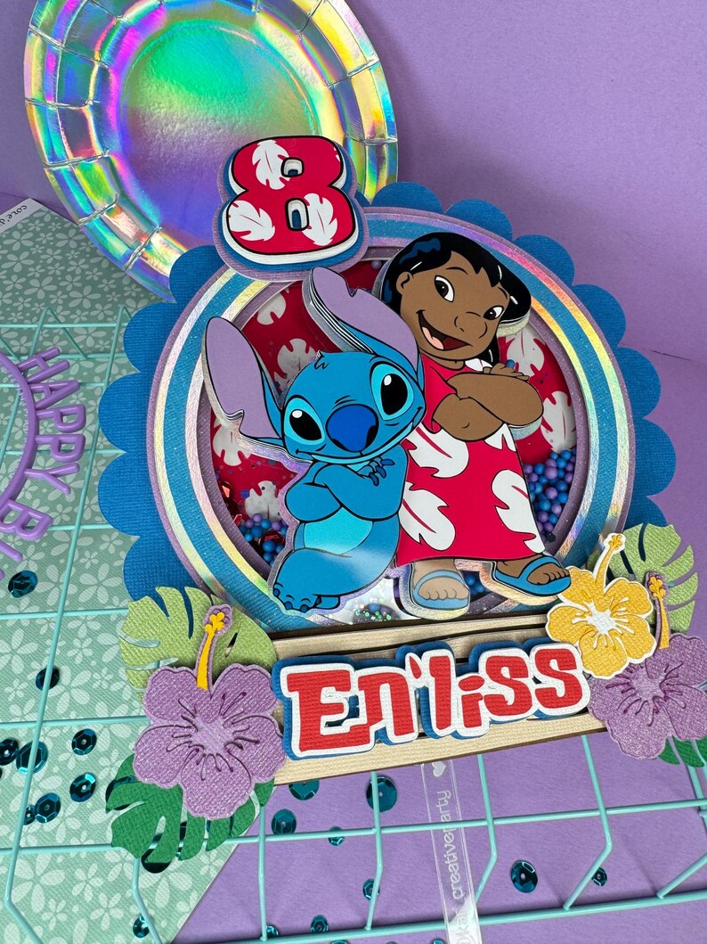 Może przedstawiać: Kolorowa dekoracja urodzinowa z postaciami Stitcha i Lilo z filmu Disneya Lilo & Stitch. Projekt zawiera cyfrę 8, słowo "Eniiss" i kwiatowe akcenty. Tło obejmuje holograficzny talerz i kratkę.