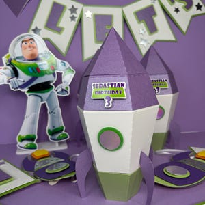 Può includere: Un set di decorazioni per feste di compleanno viola, bianco e verde con un design a forma di razzo. Il set include uno striscione con la scritta "LET'S" e un ritaglio di Buzz Lightyear. I razzi hanno il testo "SEBASTIAN BIRTHDAY 3".