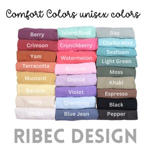 May include: A color chart displays a variety of Comfort Colors unisex t-shirts. The shirts are folded and stacked, showcasing colors like Berry, Crimson, and Mustard. The text "Comfort Colors unisex colors" and "RIBEC DESIGN" are also visible.