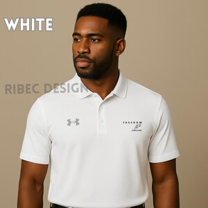 Op de afbeelding: Witte poloshirt met een knoopsluiting met drie knopen, korte mouwen en een kraag. Het shirt heeft de tekst "FREEDOM" en een logo op de borst. Het woord "WHITE" wordt linksboven weergegeven.