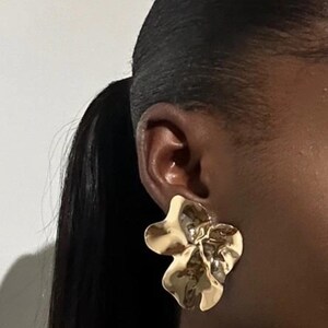 May include: Gold flower-shaped earrings with a textured, organic design.
