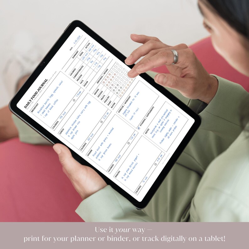 A woman holding a tablet displaying the digital version of the daily food journal with sample text filled in. Demonstrates how the tracker can be used on an iPad or other digital devices with note-taking apps
