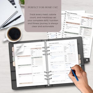 A printed daily food journal page with handwritten sample data inserted in a binder. A man's hand is shown writing on it, with a laptop, papers, and coffee cup on a desk – depicting real-life usage at home or office.
