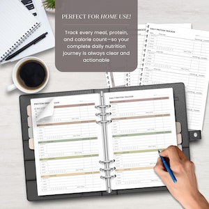 Puede incluir: Un archivador de cuero negro abierto en una p&aacute;gina de "Daily Protein Tracker", con un bol&iacute;grafo en la mano escribiendo en la p&aacute;gina. El texto "PERFECT FOR HOME USE!" est&aacute; en la parte superior, con el texto "Track every meal, protein, and calorie count" debajo.