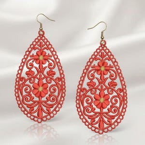 May include: A pair of red filigree teardrop earrings. Each earring features a floral design with gold-coloured accents and a decorative border. The earrings have gold-coloured ear wires.