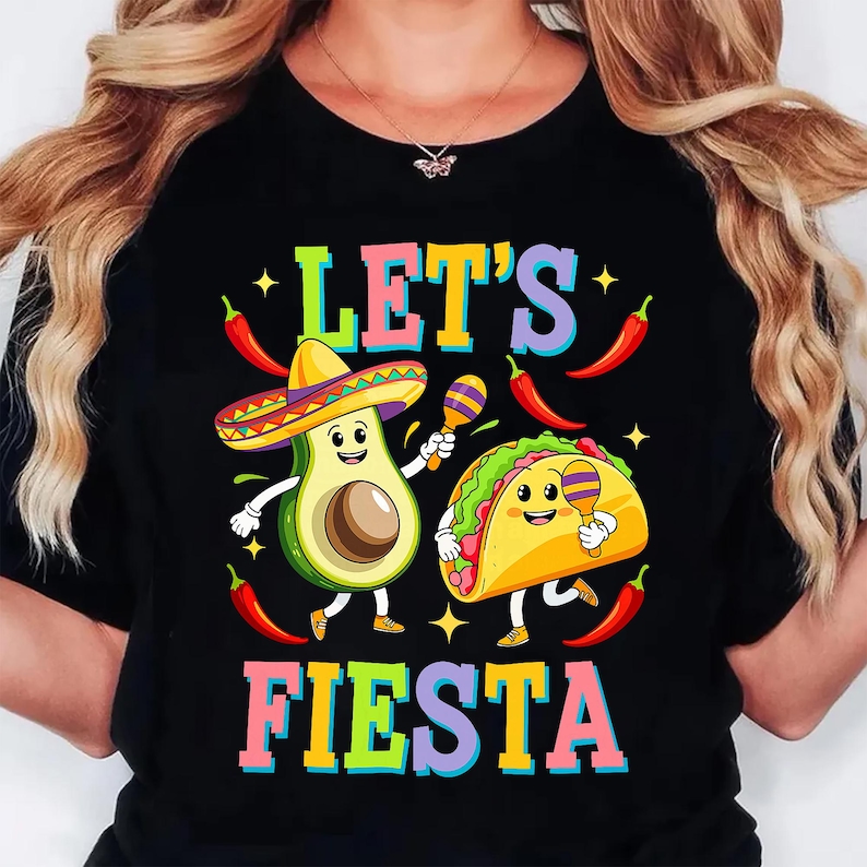 May include: Black t-shirt with the words "LET'S FIESTA" in colourful letters. The graphic shows a smiling avocado in a sombrero and a smiling taco, both with maracas, alongside chilli peppers and stars.