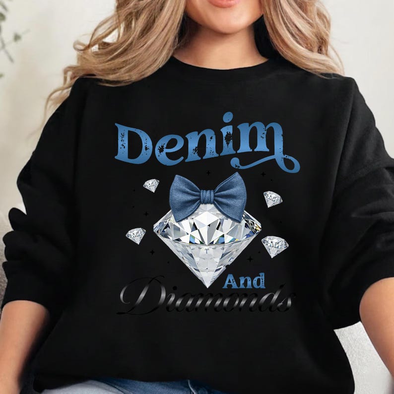 May include: Black sweatshirt with the text "Denim And Diamonds" in blue and black script. A large diamond with a blue bow tie is centered on the shirt, surrounded by smaller diamond graphics.