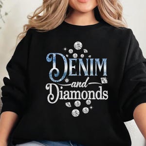 May include: Black sweatshirt with the text "Denim and Diamonds" in a blue glitter font and white script. The design includes diamond illustrations. The sweatshirt is a casual, everyday garment.