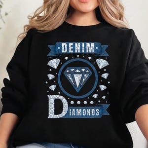 May include: Black sweatshirt with a blue graphic that reads "DENIM DIAMONDS." The design features a large diamond in a circle, surrounded by smaller diamonds. The word "DENIM" is on a banner above the diamond, and "DIAMONDS" is below.