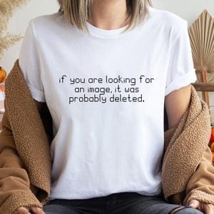 May include: A white short-sleeved t-shirt featuring black pixelated text centred on the chest that reads, "if you are looking for an image, it was probably deleted." The shirt has a crew neckline and a standard fit with cuffed sleeves.