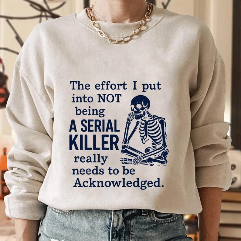 May include: A cream-coloured sweatshirt featuring the text "The effort I put into NOT being A SERIAL KILLER really needs to be Acknowledged." A blue skeleton graphic is on the right.