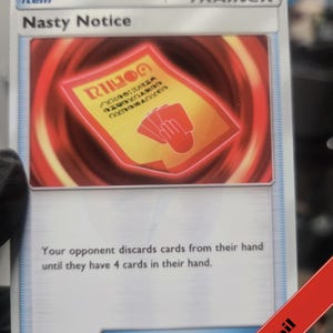 Puede incluir: Una carta de Entrenador Objeto Nasty Notice del juego de cartas coleccionables Pok&eacute;mon. La carta muestra una ilustraci&oacute;n de un papel rojo con un icono de mano y texto sobre un fondo rojo giratorio. El texto dice: Your opponent discards cards.