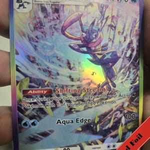 Puede incluir: Una carta coleccionable hologr&aacute;fica de Greninja EX, evoluci&oacute;n de fase 2 de Frogadier con 170 HP. La carta muestra la habilidad Shifting Stream y el ataque Aqua Edge, con un borde de l&aacute;mina arco&iacute;ris y una ilustraci&oacute;n din&aacute;mica del personaje.