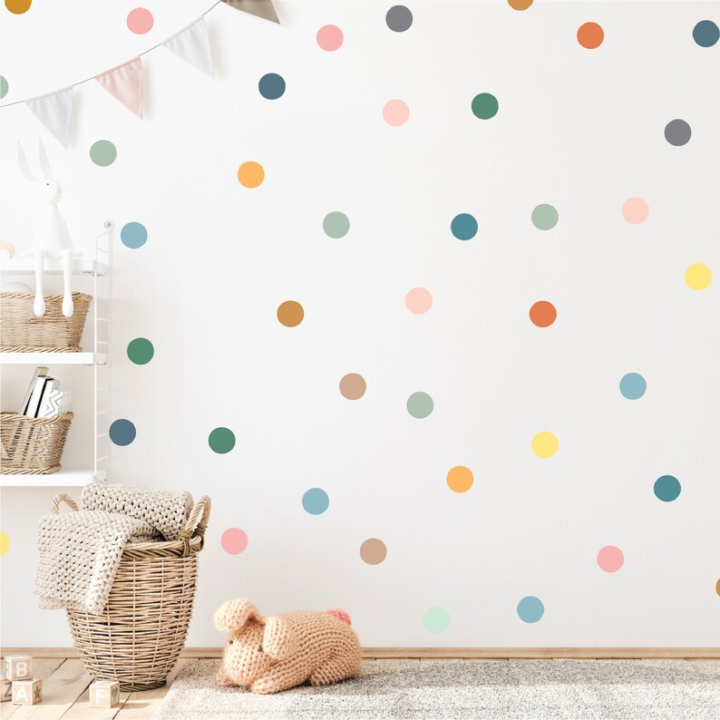 Puede incluir: Una pared blanca con lunares coloridos en varios tonos de azul, verde, naranja, rosa y amarillo. Los lunares est&aacute;n dispuestos en un patr&oacute;n aleatorio.