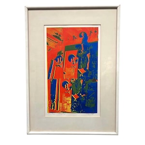 May include: Abstract art print in a white frame. The artwork features a vibrant composition of red, blue, green, and yellow shapes. The print has a modern aesthetic, suitable for home or office decor.