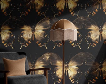 May include: A room featuring a black butterfly wallpaper with gold accents. A gray armchair with a brown pillow sits in front of the wall. A floor lamp with a beige lampshade and a framed picture of an astronaut are also present.