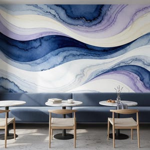May include: A modern interior featuring a wall mural with a watercolor design in shades of blue, white, and purple. The room includes a blue sofa, round tables, and wooden chairs, creating a stylish and inviting space.