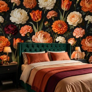 May include: A bedroom with a floral wallpaper featuring orange, white, and burgundy flowers on a black background. The bed has a green tufted headboard, orange pillows, and a beige and orange bedspread with a burgundy throw blanket.