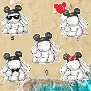 May include: A collection of white bunny stickers, each wearing a black hat with "2026" and "Custom Text" on it. Some bunnies have sunglasses, a bow tie, a red balloon, or a red polka dot bow.