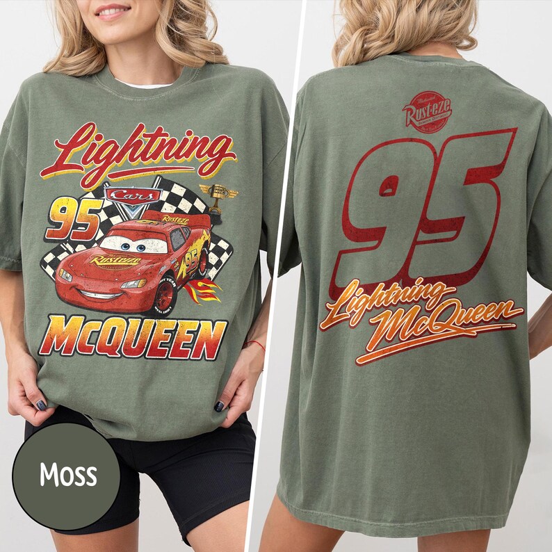 Puede incluir: Camiseta verde musgo con Lightning McQueen de la pel&iacute;cula Cars. El frente muestra "Lightning McQueen", "95" y una bandera a cuadros. La parte trasera muestra un gran "95" y "Lightning McQueen" en rojo.
