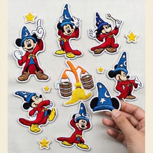 May include: A collection of embroidered patches featuring Mickey Mouse in a wizard costume. The patches showcase Mickey in a red robe and blue wizard hat, with yellow stars and a broom. The patches are on a light background.