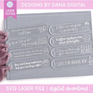 May include: Eight clear acrylic rectangular bookmarks with rounded ends and holes for tassels. Each features white engraved coffee-themed text and illustrations, including phrases like Today's good mood is sponsored by coffee and Coffee makes me user-friendly.