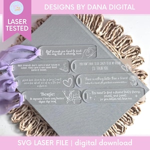 Puede incluir: Marcadores de acrílico transparente con texto e ilustraciones grabadas en blanco. Los marcadores tienen citas sobre la amistad, incluyendo "Bestie: It means I love you better than the rest." Una cinta morada está adjunta. El texto "Laser Tested" es visible.