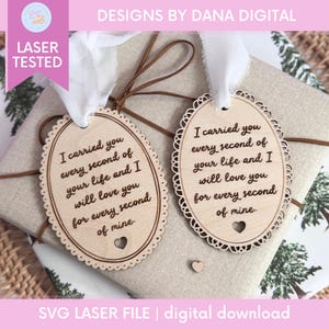 Op de afbeelding: Twee houten cadeaulabels met een geschulpte rand en de tekst "Ik heb je elke seconde van je leven gedragen en ik zal van je houden voor elke seconde van mij." Onderaan is een klein hartje uitgesneden. De labels zijn vastgebonden met een wit lint.