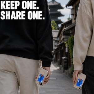 May include: Two smartphones with clear cases featuring a blue rectangular sticker with a graphic of a burning match and Japanese text. The text KEEP ONE. SHARE ONE. is displayed in white bold letters at the top left of the image.
