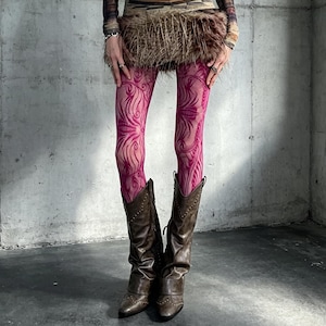 Könnte beinhalten: Transparente magentafarbene Strumpfhose mit dunkelrosa wirbelndem Blumenmuster, kombiniert mit einem braunen Kunstfell-Minirock und braunen Leder-Cowboystiefeln mit metallischen Nietendetails entlang der Nähte und spitzer Zehenpartie.
