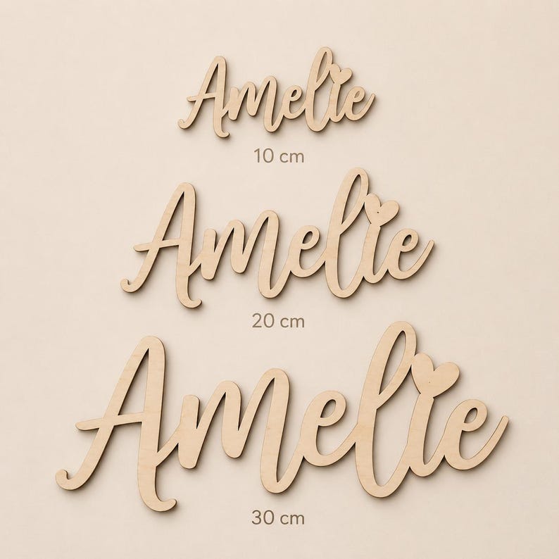 May include: Three wooden cutouts of the name "Amelie" in a cursive font. The sizes are 10 cm, 20 cm, and 30 cm. Each name has a heart detail. The wood has a natural, light brown color.