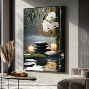 Op de afbeelding: Een ingelijste print van een zen-tuinscène met witte orchideeën, bamboestokken en gladde grijze stenen die in een vijver met rimpelend water zijn gerangschikt. Twee brandende kaarsen staan op de stenen.