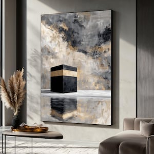 May include: Abstract art print featuring a black cube with a gold band, set against a backdrop of gray, black, and gold brushstrokes. The artwork is framed and reflects on a mirrored surface, creating a modern and sophisticated aesthetic.