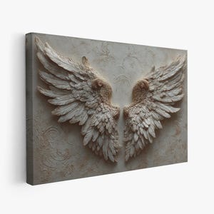 May include: A rectangular canvas print featuring a detailed relief of two symmetrical angel wings. The wings are rendered in a neutral color palette of beige and off-white, with intricate feather detailing. The background has a subtle, textured pattern.