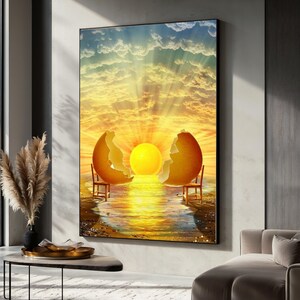 Puede incluir: Una impresión artística enmarcada representa una escena surrealista del amanecer. Un gran sol amarillo brilla entre dos mitades de cáscara de huevo, con dos pequeñas sillas frente al sol. El cielo es una mezcla de amarillo, naranja y azul.