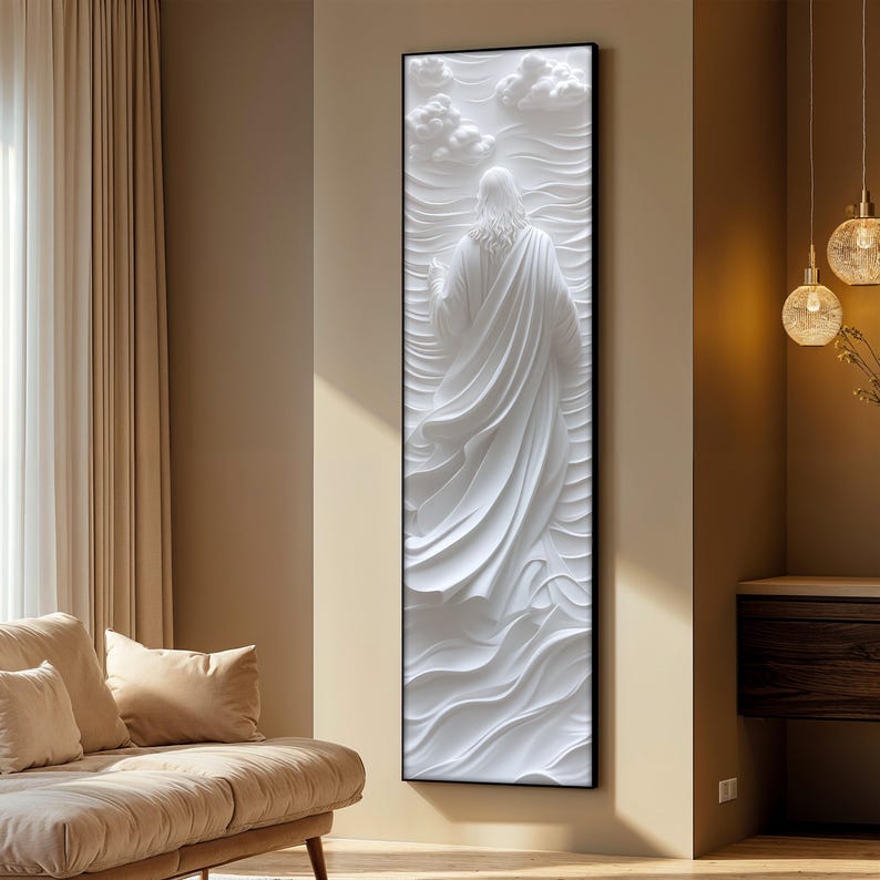 K&ouml;nnte beinhalten: Wei&szlig;e 3D-Wandskulptur einer Person in einem flie&szlig;enden Gewand, vor einem strukturierten Hintergrund. Die Skulptur ist in Schwarz gerahmt und an einer wei&szlig;en Wand montiert.