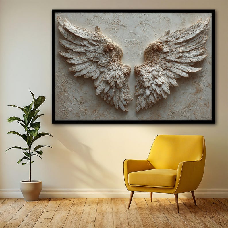 May include: A framed wall art piece featuring a pair of detailed, textured angel wings in shades of cream and beige. The wings are set against a textured background with a black frame. The artwork is displayed above a yellow armchair.